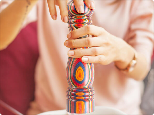 Colorful pepper grinder held by a person with a blurred background